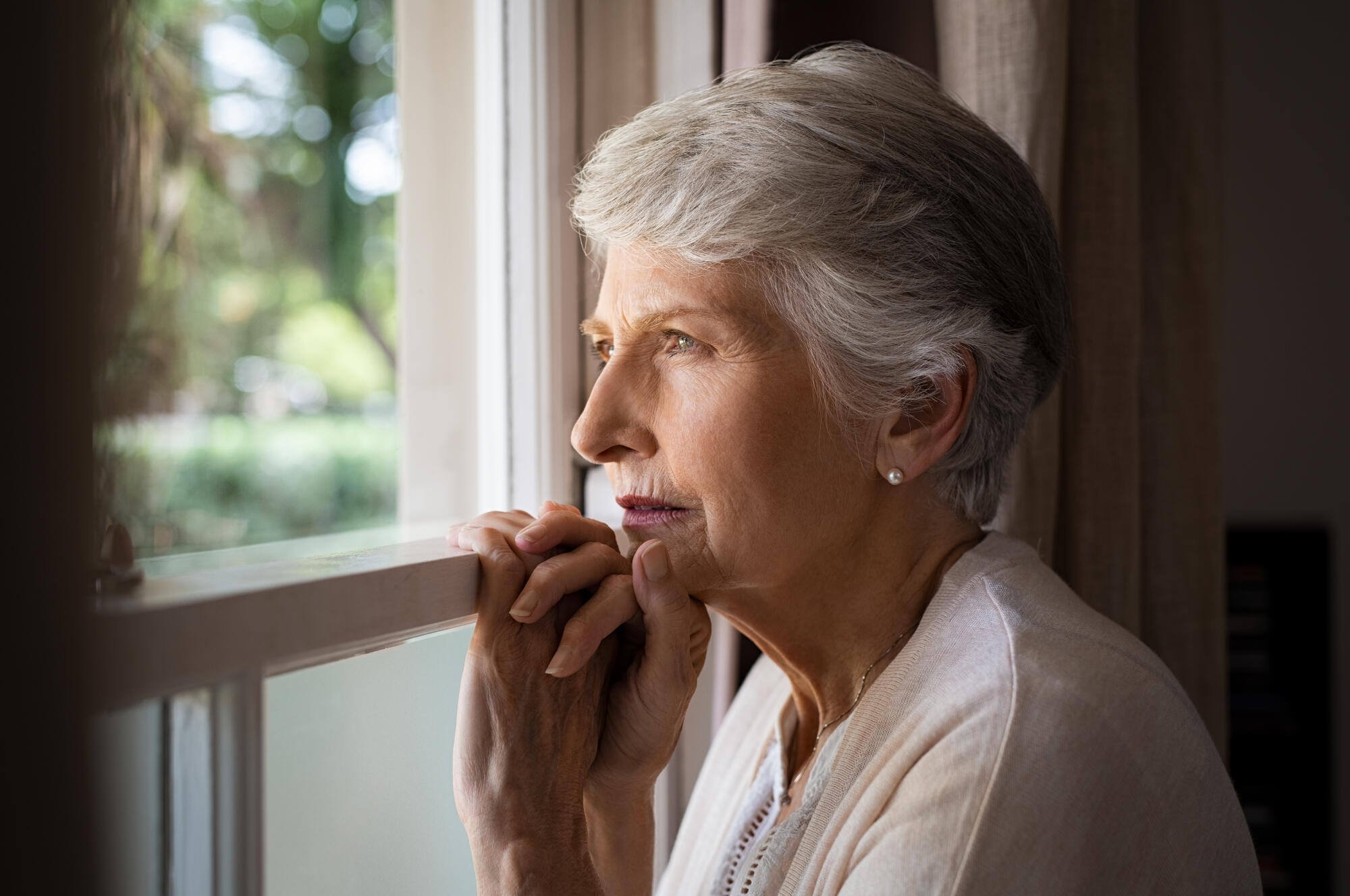 A thoughtful senior looking out the window