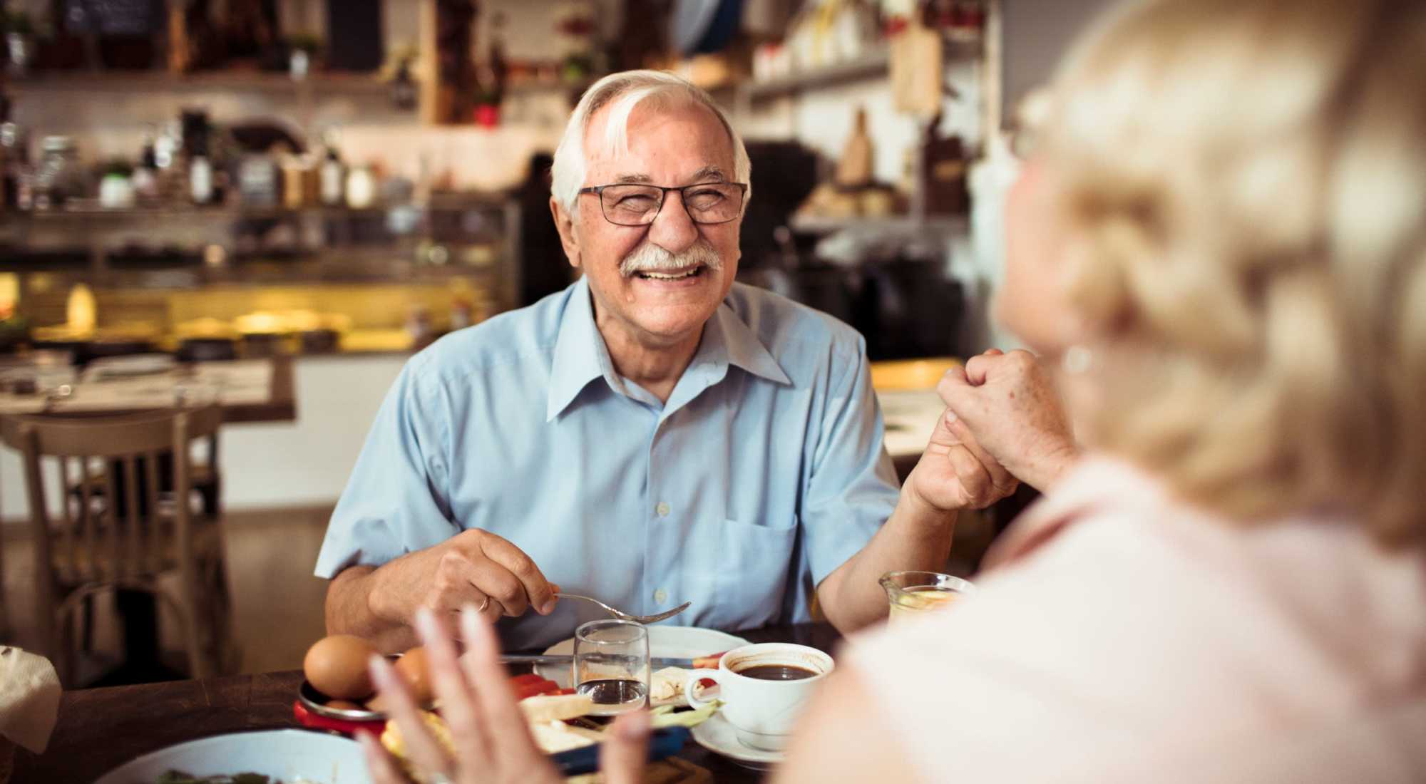 Senior man smiling with food and drink at a table