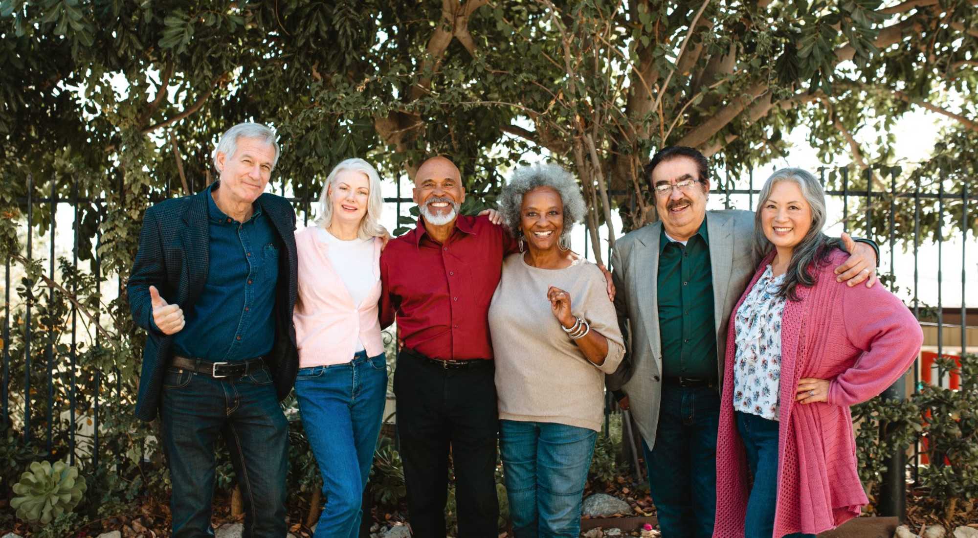 Residents and staff posing together outdoors in a garden setting