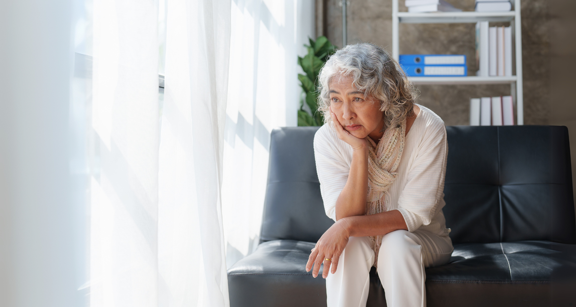 A thoughtful resident sitting quietly in a lounge area