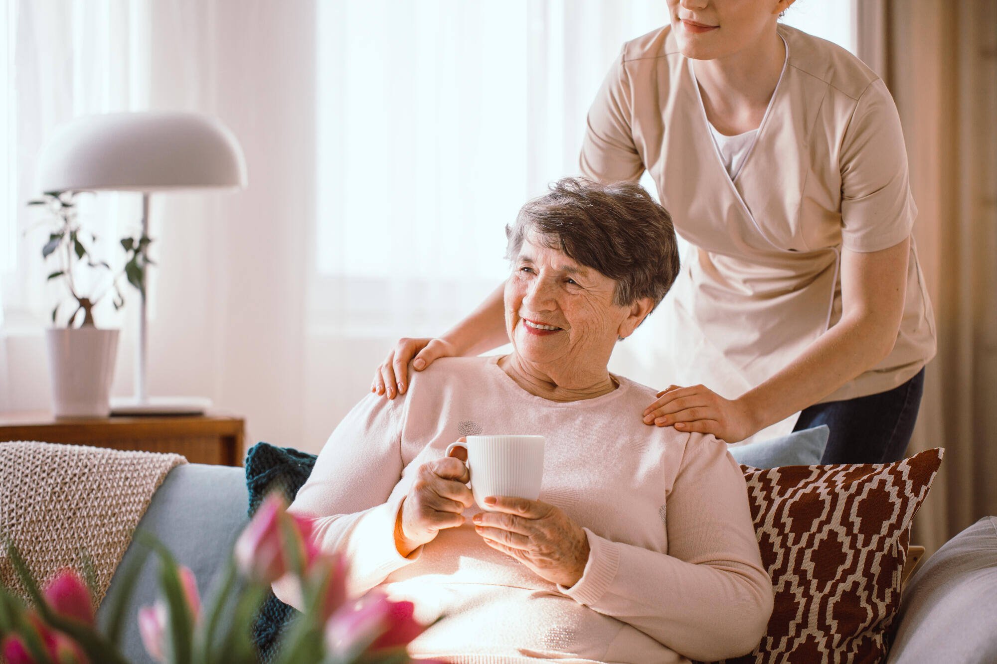Resident enjoying tea with staff member in a cozy setting