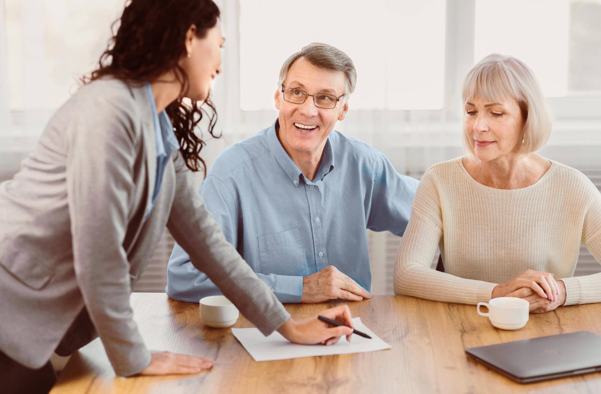 Staff member assisting happy senior residents at a table