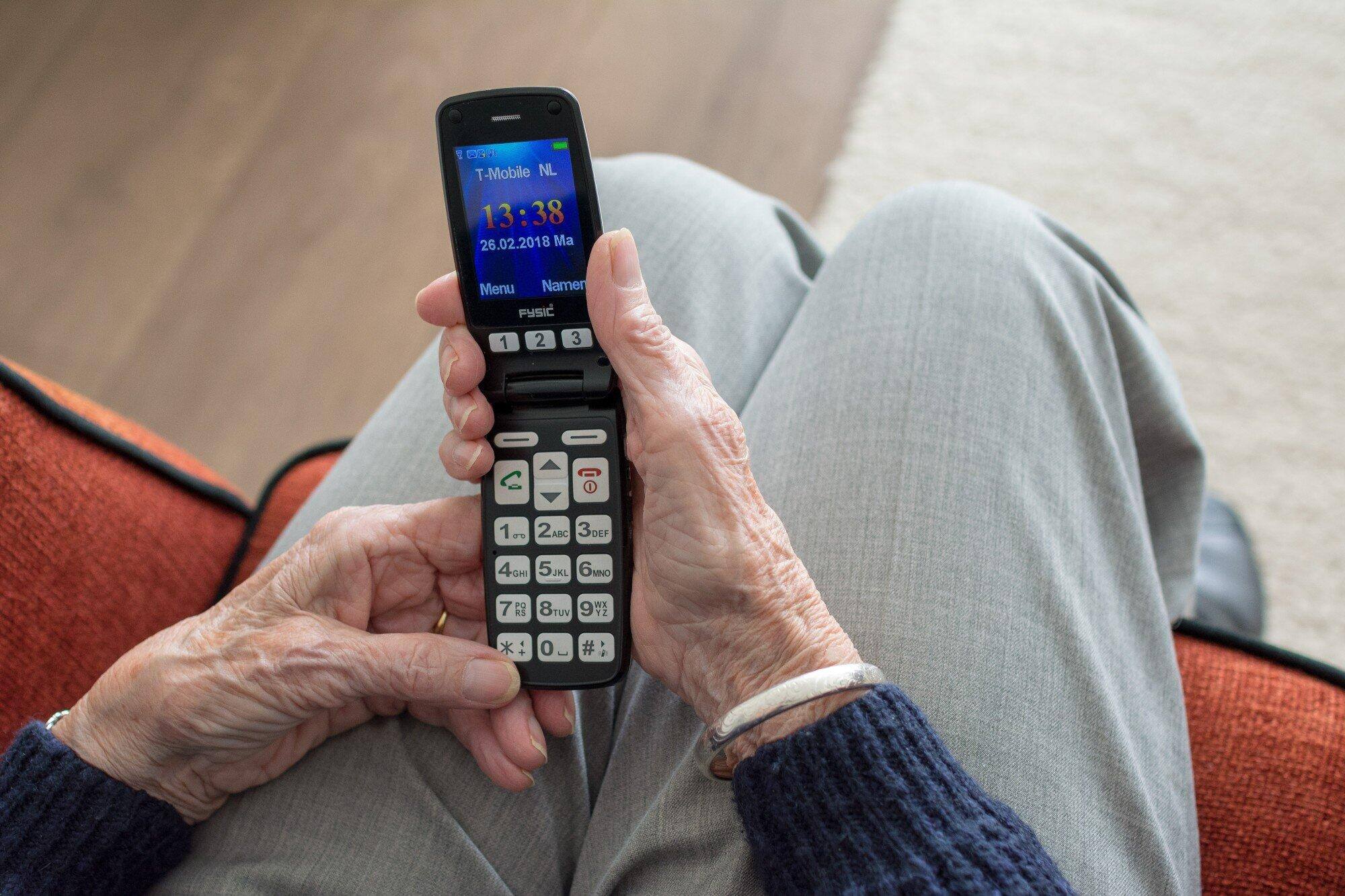 An elderly person's hand holding a mobile phone