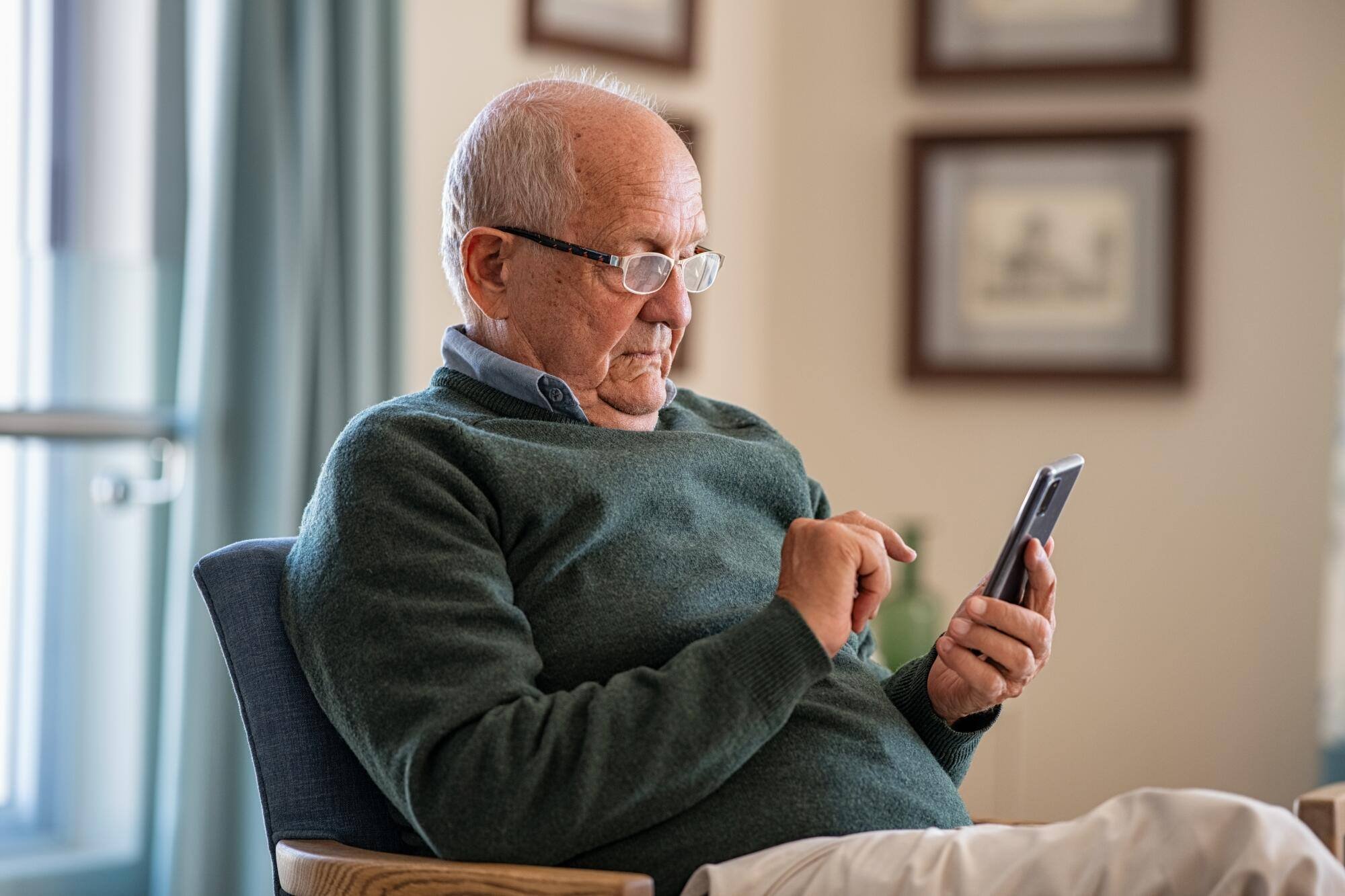 An elderly man using a smartphone indoors