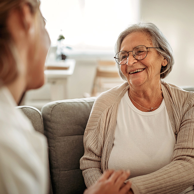 Elderly woman smiling and talking with a caregiver