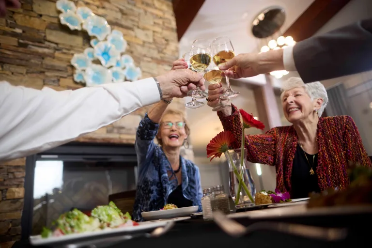 Residents toasting with drinks at a dining table