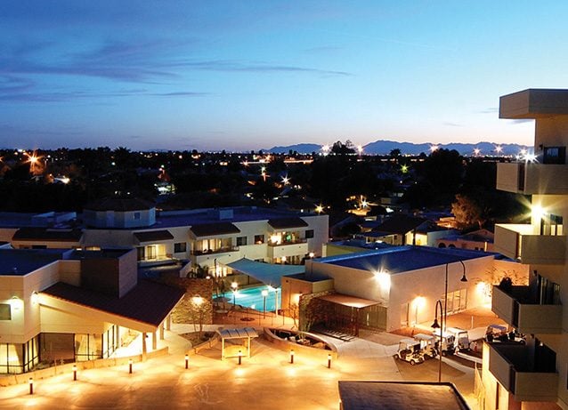 Evening view of the facility with outdoor spaces and pool