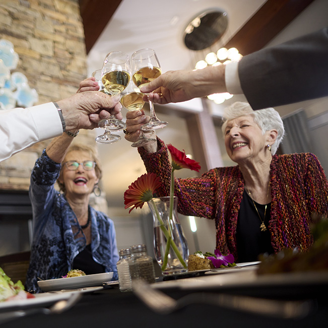 Residents toasting with drinks at a dining table