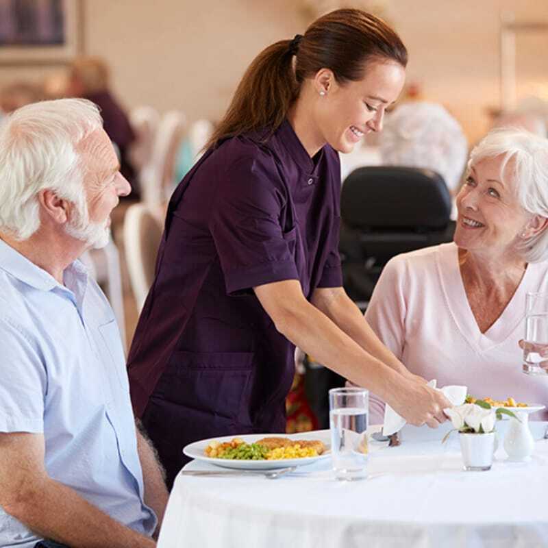 Staff serving meals to residents in a dining area