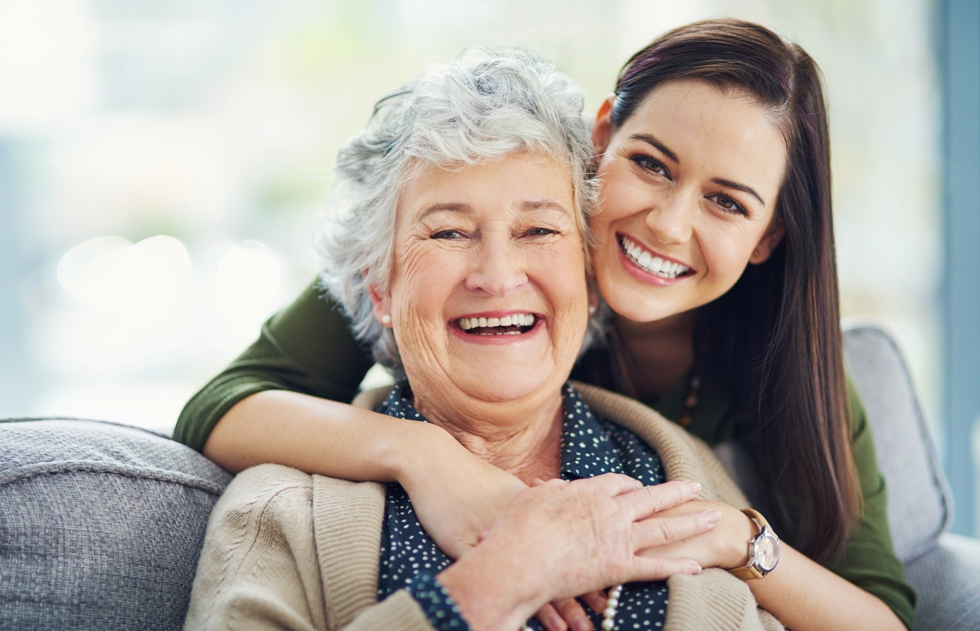 A young caregiver hugging a smiling senior resident