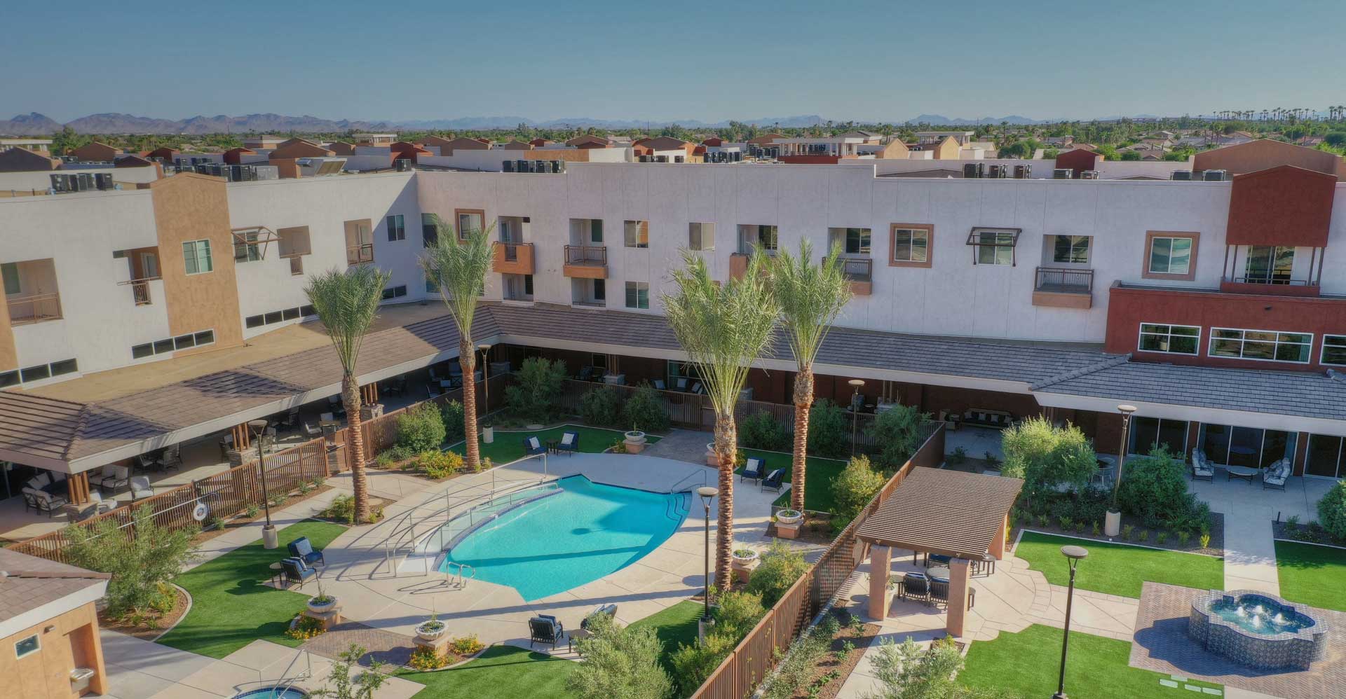 Aerial view of a senior living facility with a pool and landscaped areas