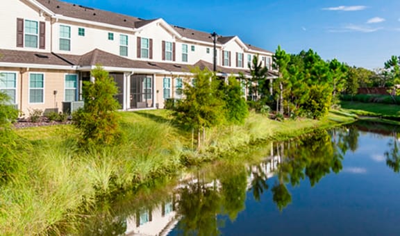 Exterior view of Village Park Senior Apartments by a pond.