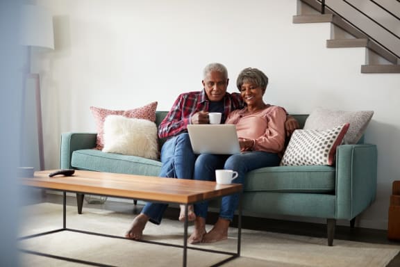 Older couple together on a sofa using a laptop