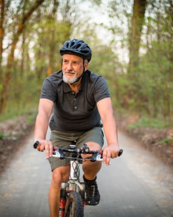 An older man biking on a nature path