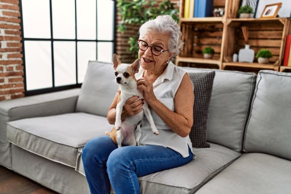 Senior woman happily holding a small dog in a cozy living room