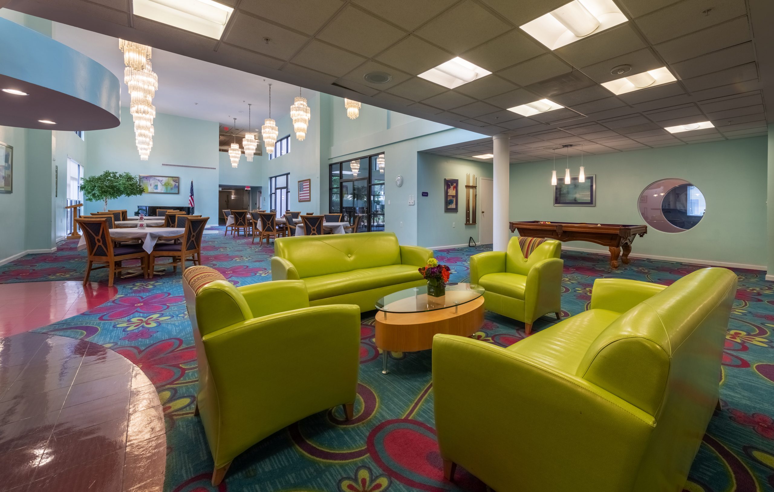 Bright lounge area with green sofas and colorful carpet