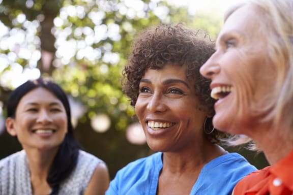 Three women smiling and enjoying each other's company outdoors