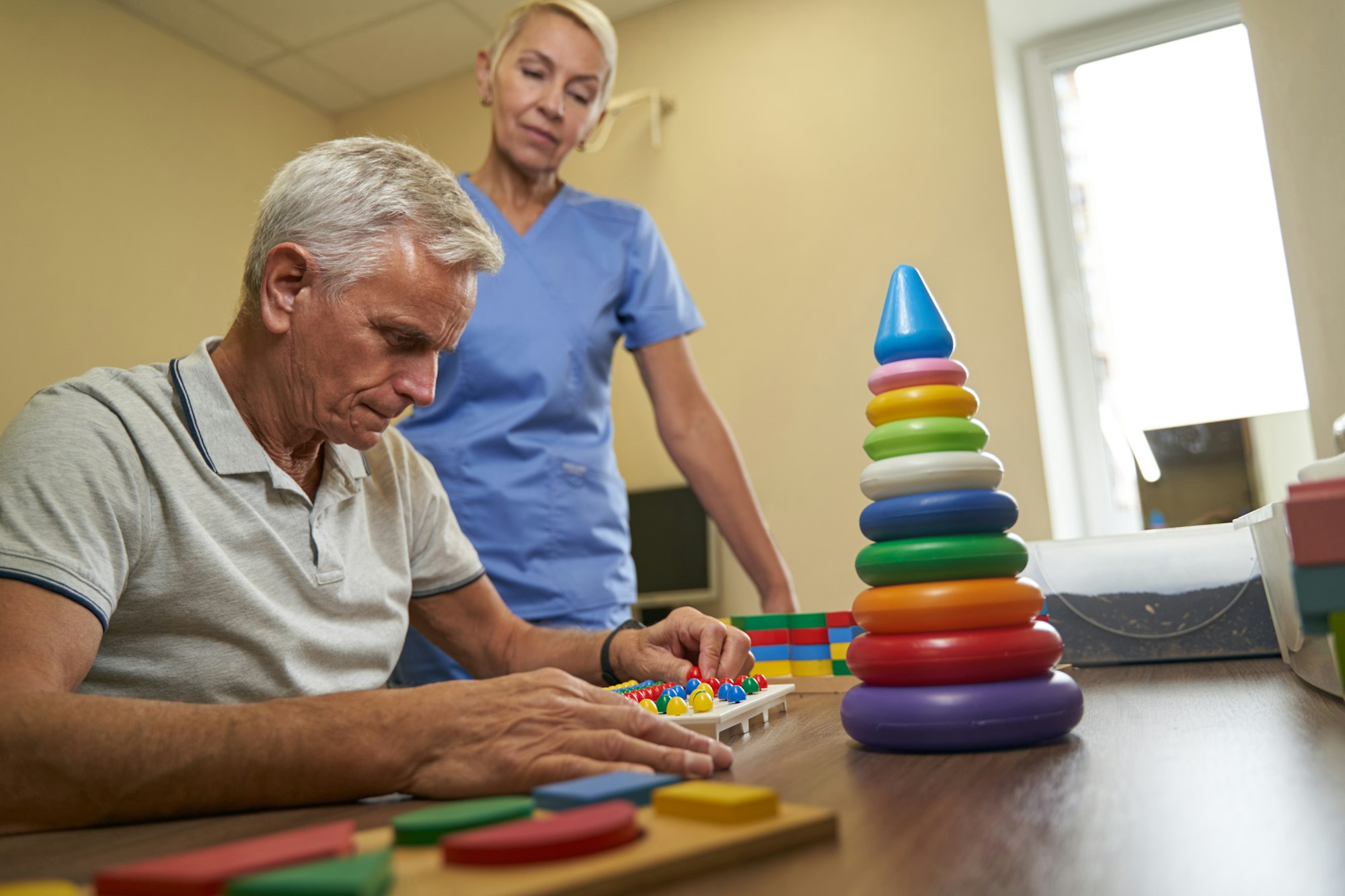 A caregiver assisting a senior with an activity in a bright room
