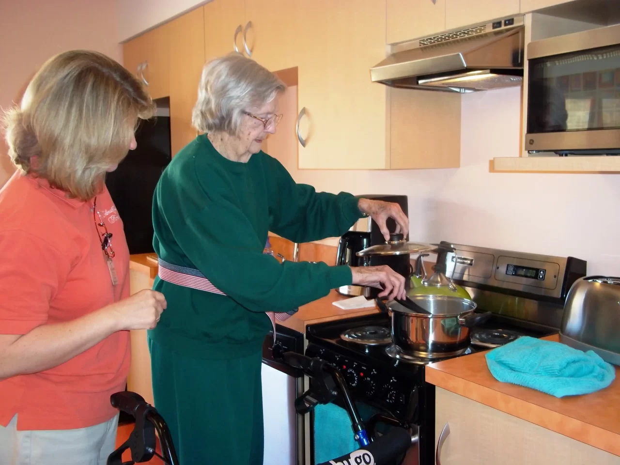 Resident cooking in a kitchen with staff assistance