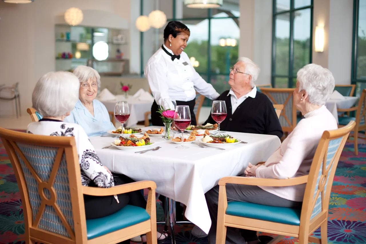 Residents enjoying a meal in the dining room with a server