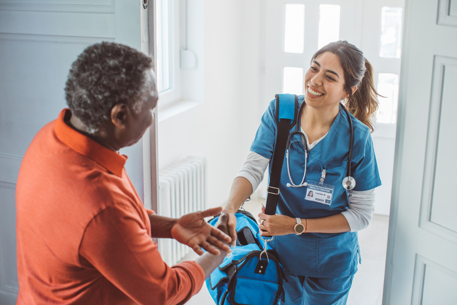 Healthcare staff greeting a resident indoors