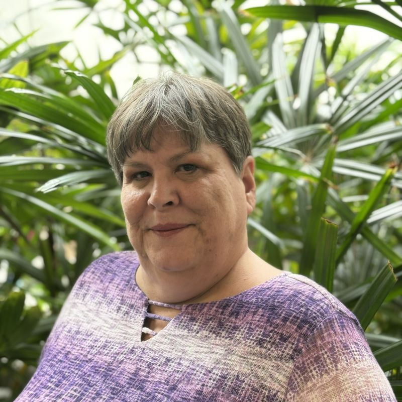 Woman smiling among tropical plants.