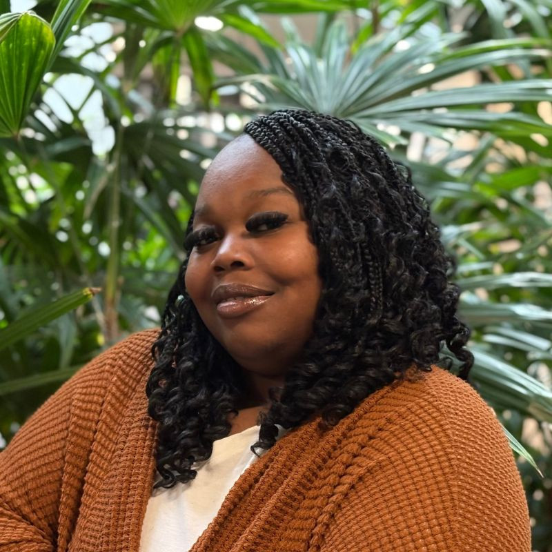 A resident smiling in a lush indoor setting.