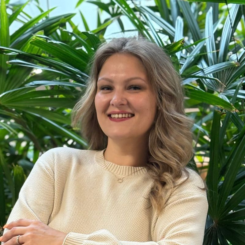 Woman smiling surrounded by greenery indoors