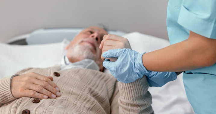 Healthcare worker holding elderly man's hand