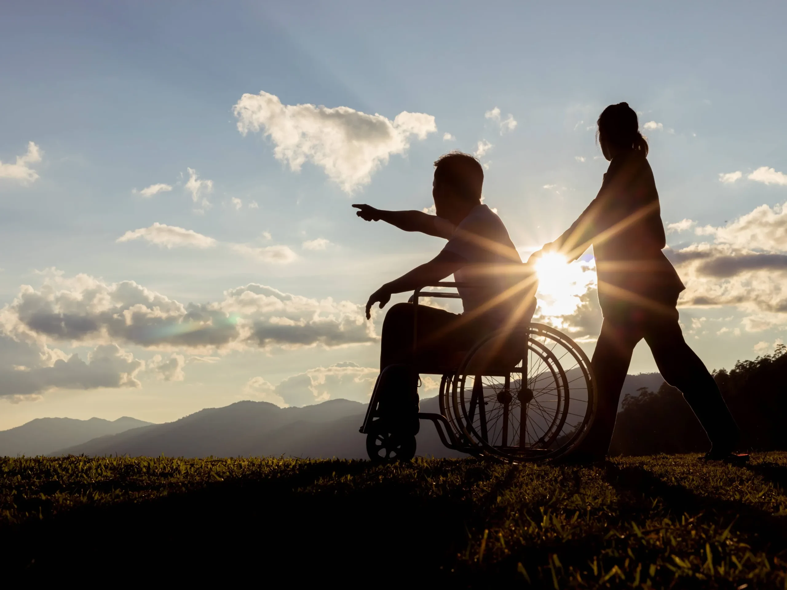 A caregiver assists a resident in a wheelchair outdoors.