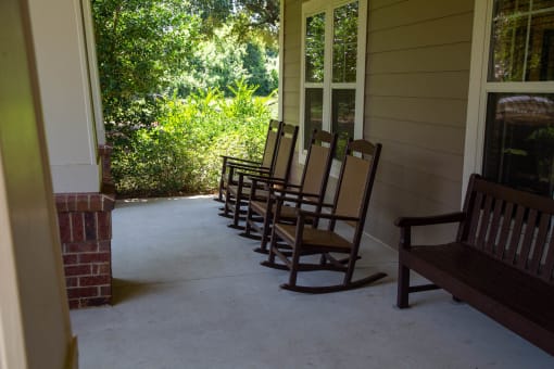 Rocking chairs on a porch surrounded by greenery.