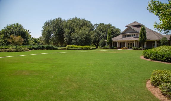 Spacious green lawn with a building in the background.
