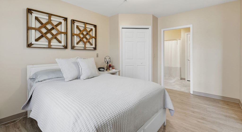 Bright interior of a resident room with bed and decor.