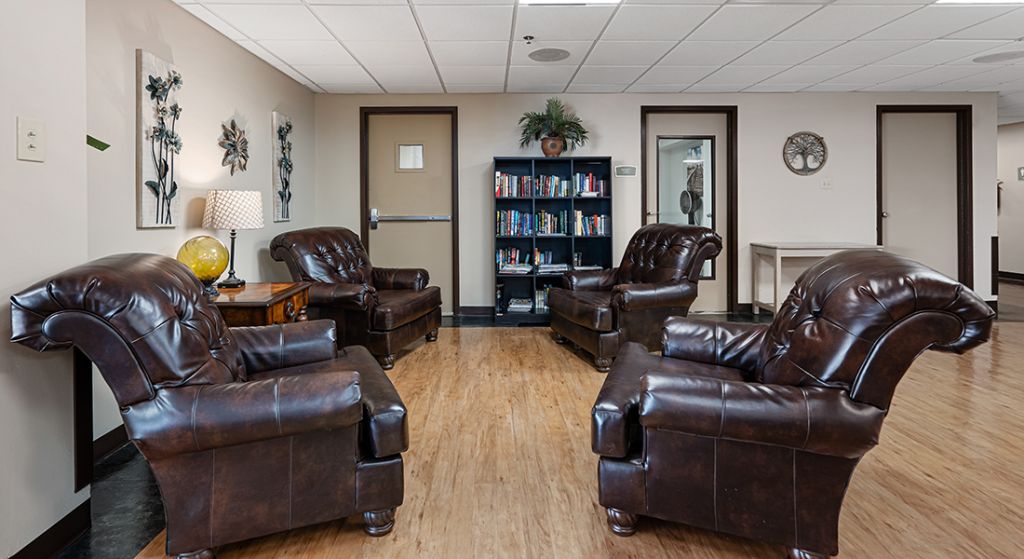 Seating area with leather chairs and bookshelf.