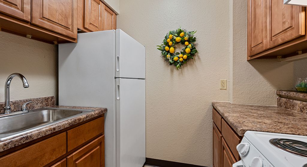 Compact kitchen with wooden cabinets and a lemon wreath.