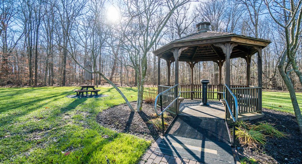 Gazebo surrounded by a green lawn and trees