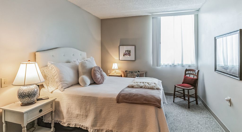 Cozy bedroom with a bed and warm lighting.