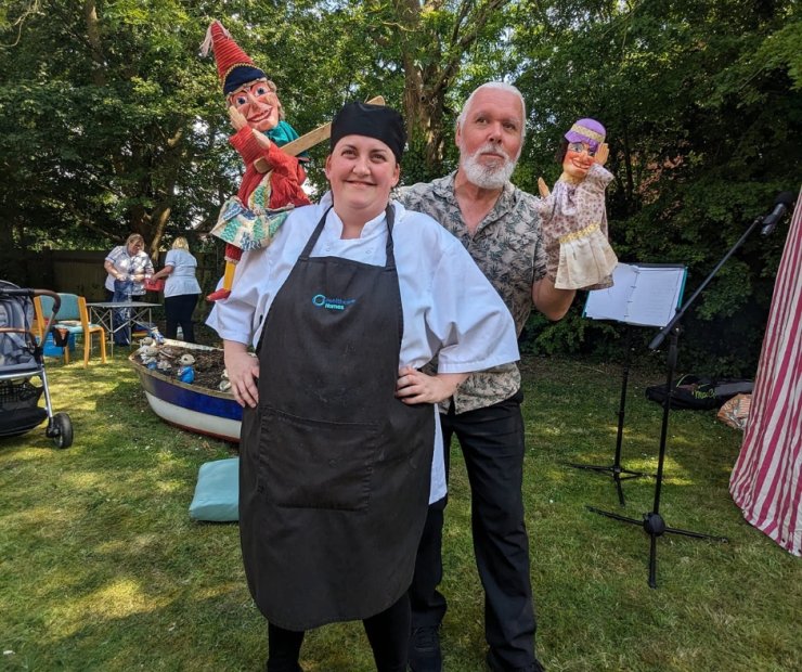 Staff member and performer with puppets in a garden