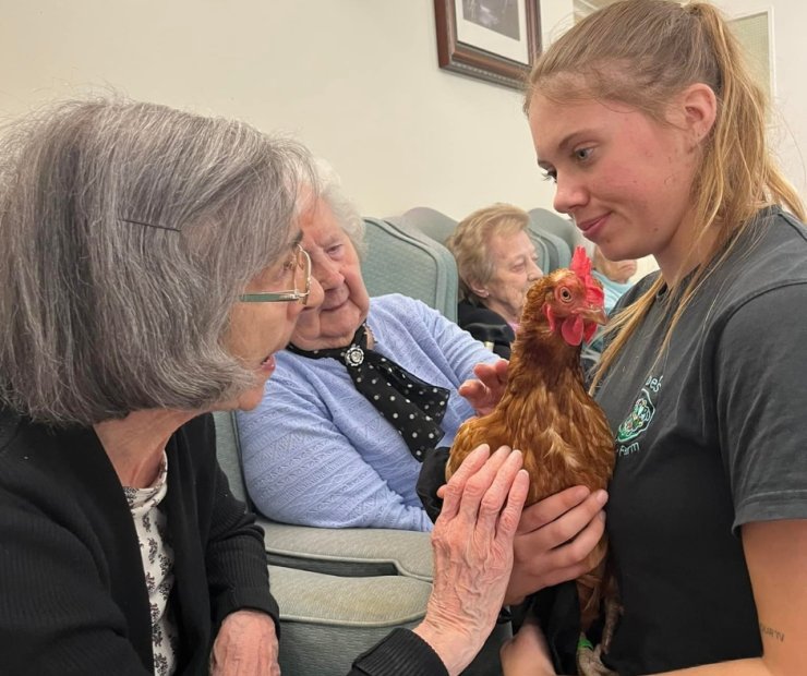 Residents interacting with a staff member and a chicken.