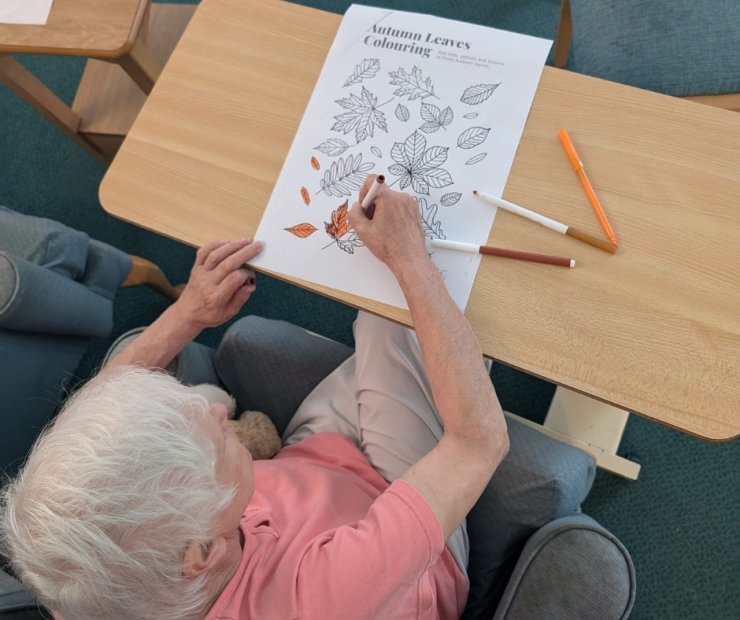 Resident coloring autumn leaves at a table.