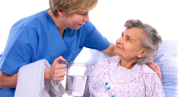 Nurse assisting an elderly woman in a care setting.