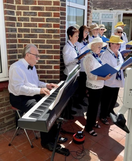 Seniors singing outdoors with a pianist