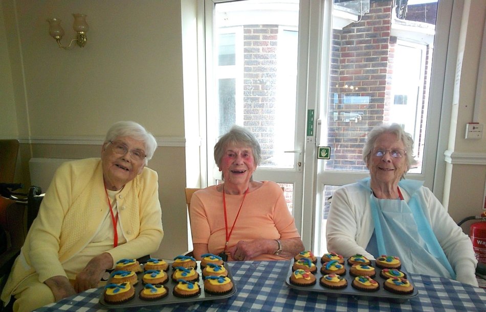 Three residents with decorated cupcakes in a common area.