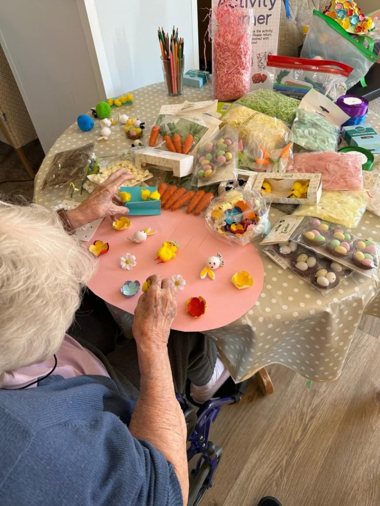 Resident crafting with colorful materials at a table