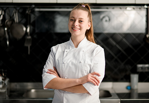 Chef in white uniform smiling in kitchen