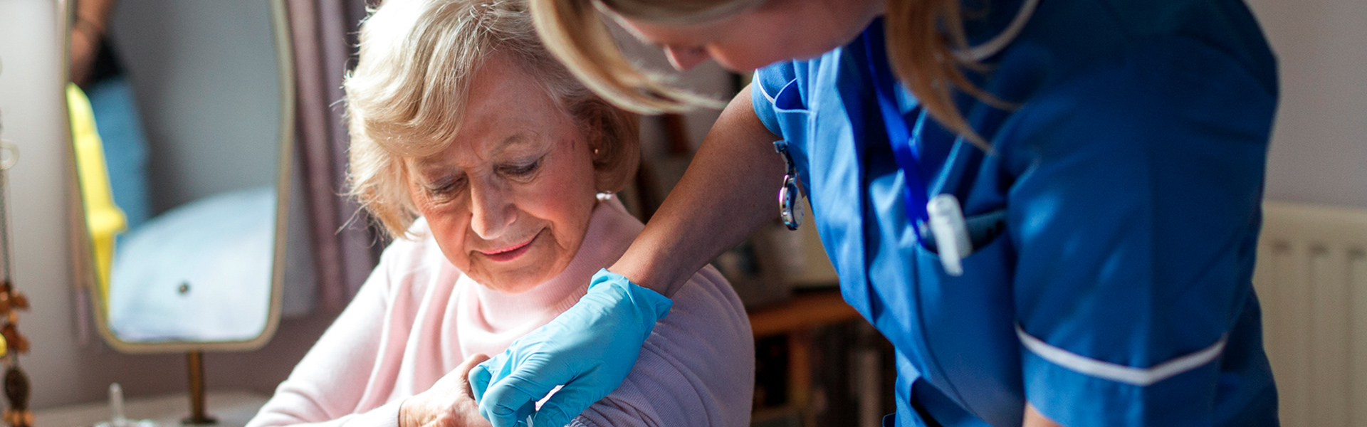 Nurse administering a vaccine to an elderly woman.