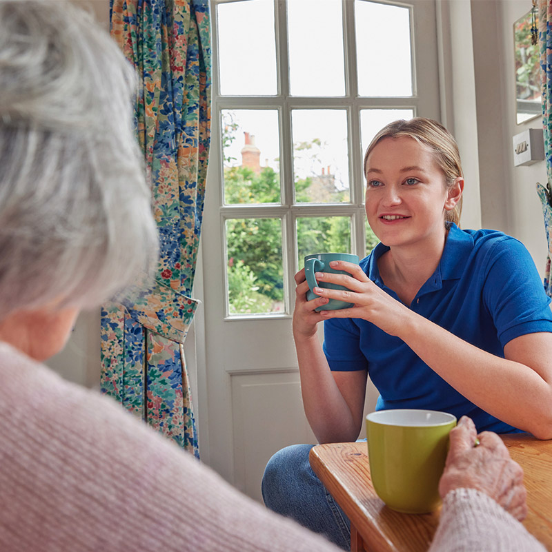 Staff member engaging with resident over tea