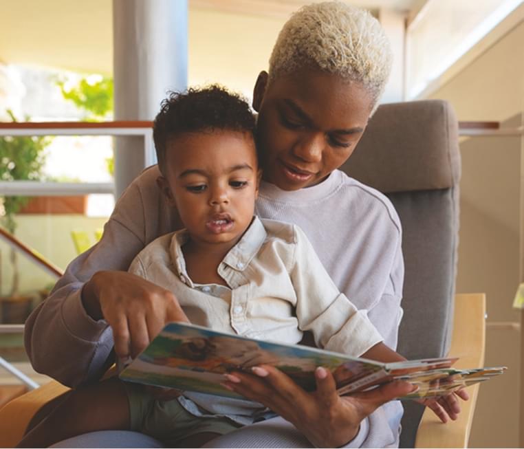 A resident reading with a child in a common area.
