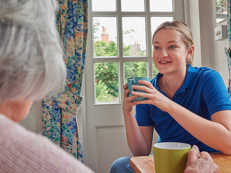Staff member engaging with a resident over tea
