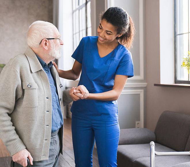 Caregiver assisting an elderly man indoors